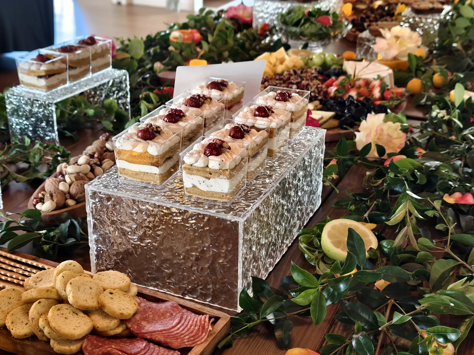 Layered dessert bars on acrylic risers surrounded by greenery