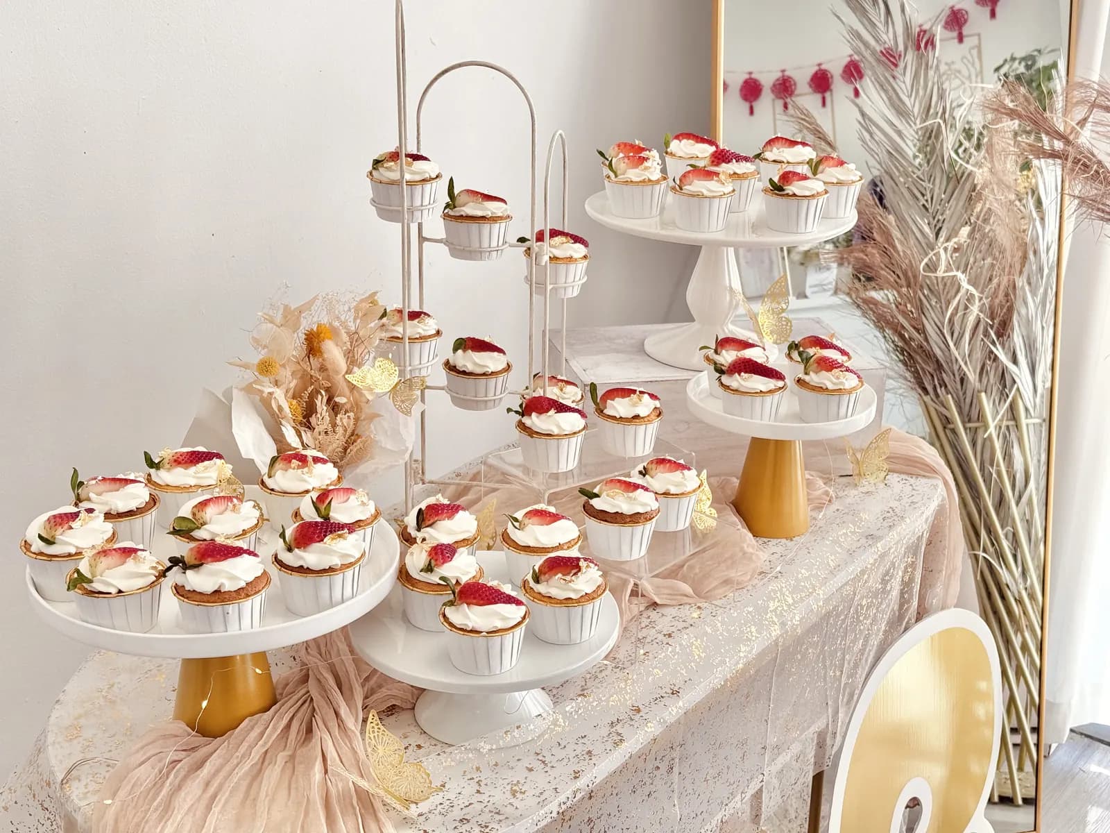 Tiered stands of strawberry-topped cups with dried florals
