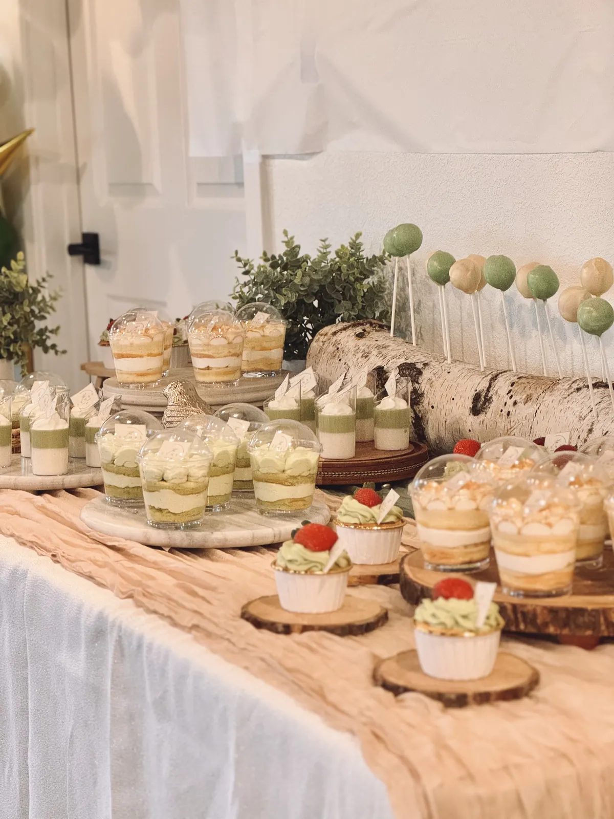 Long dessert table with mousse cups on wooden rounds