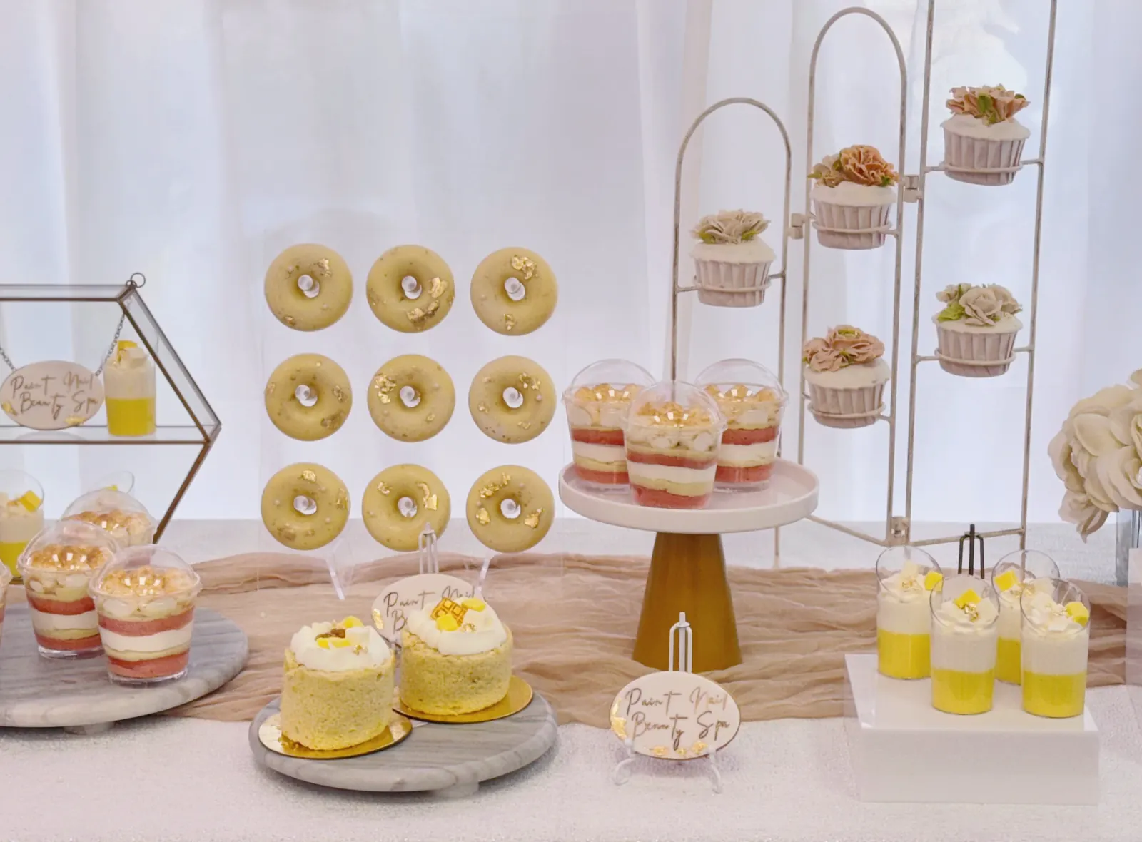 Donut wall and petite cakes on gold and white stands