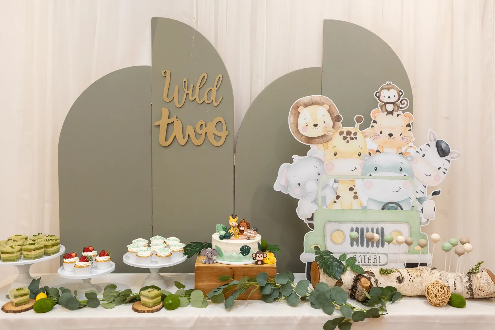 Dessert table with arched backdrop and woodland animal decorations