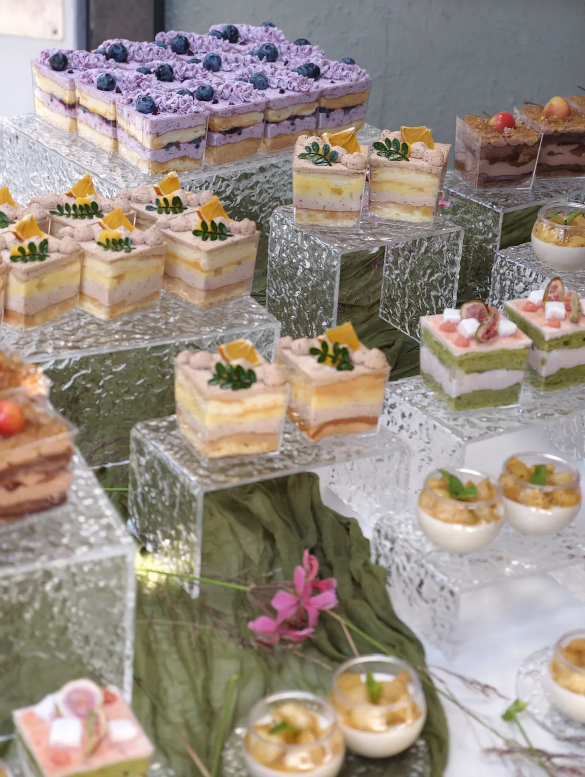 Layered mousse cups and petite cakes on clear acrylic risers