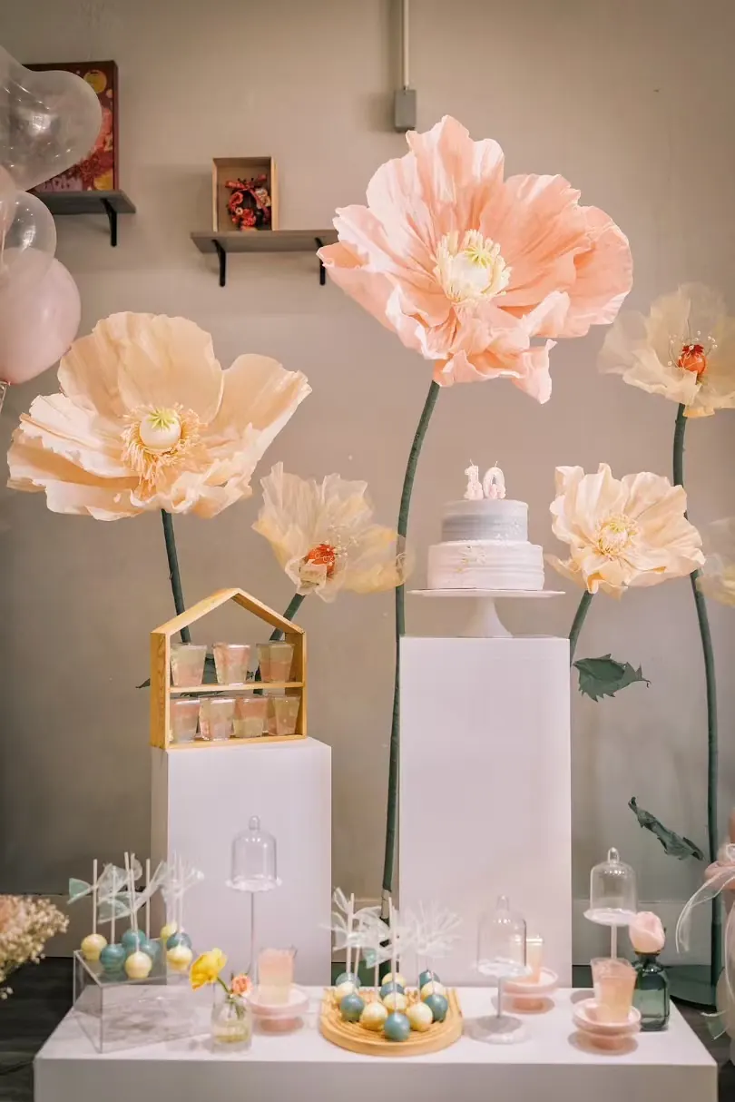 Small cake display framed by large paper flowers