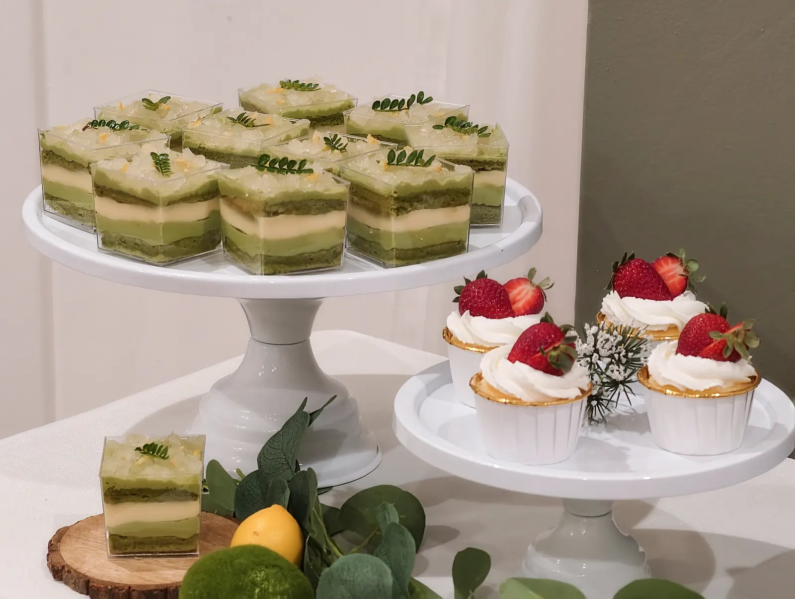 Matcha layer cakes and strawberry tarts on white cake stands