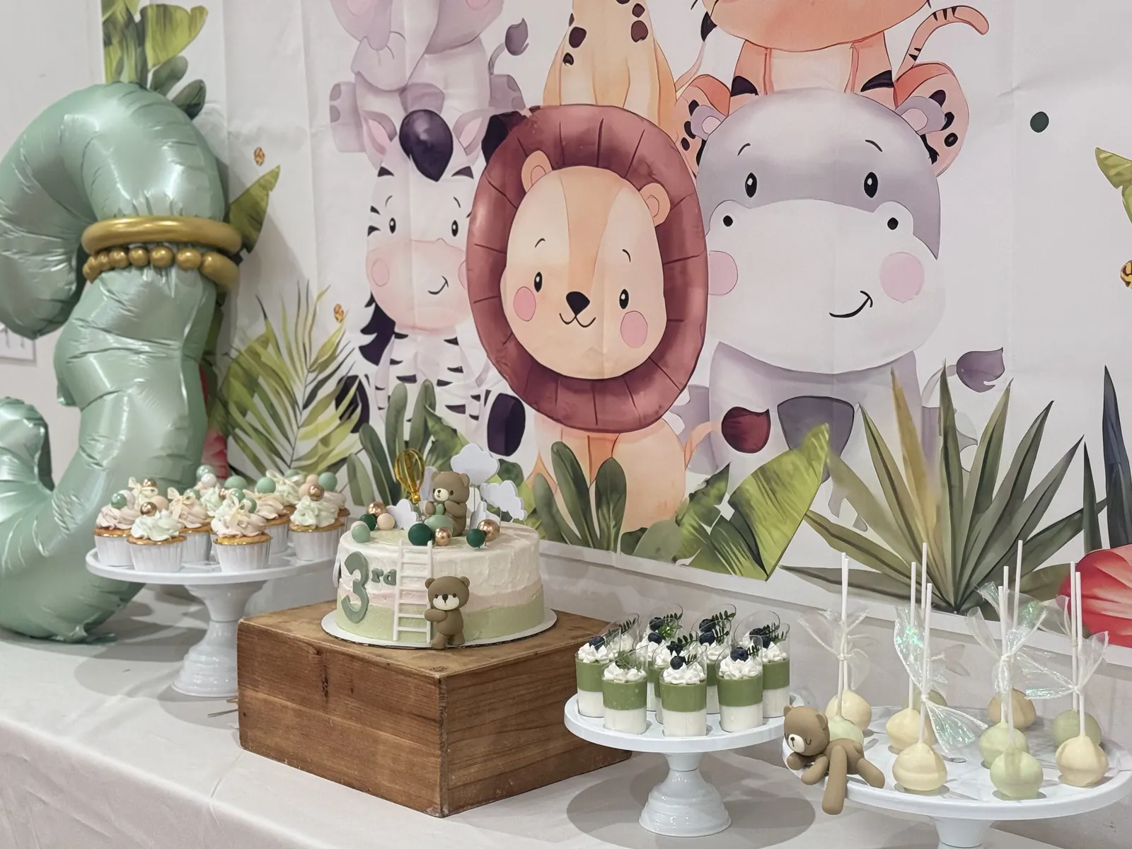 Safari-themed dessert table with mini cakes and cake pops