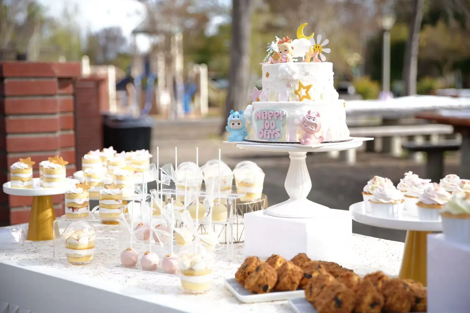 Outdoor dessert table with a tiered cake, cake pops and cookies